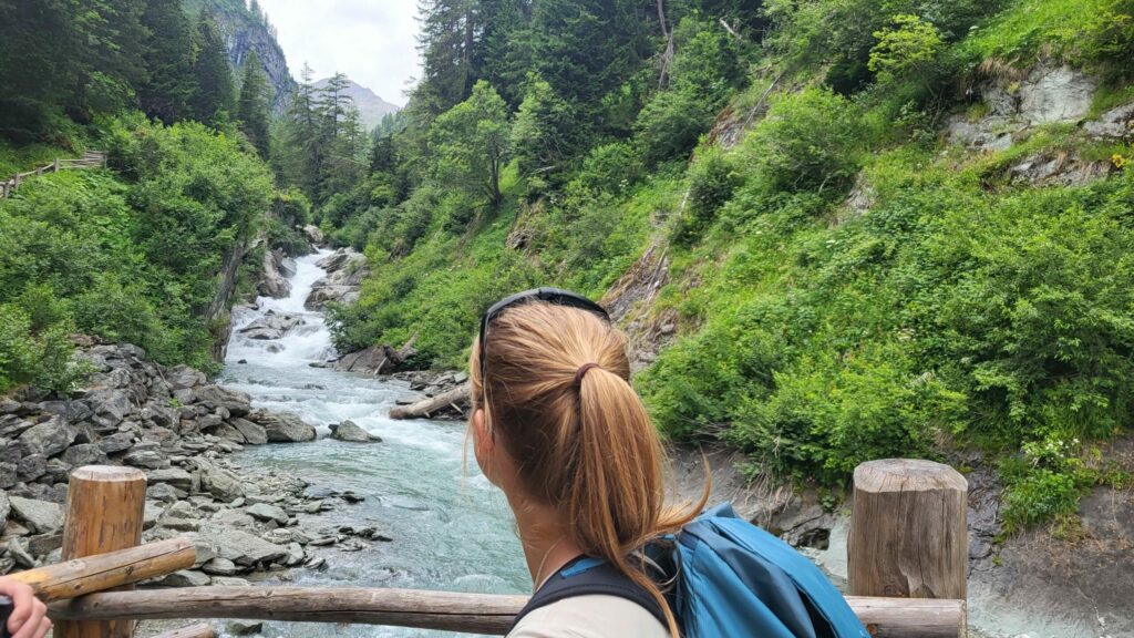 Bild zeigt eine Frau von hinten, die einen Wasserfall ansieht.