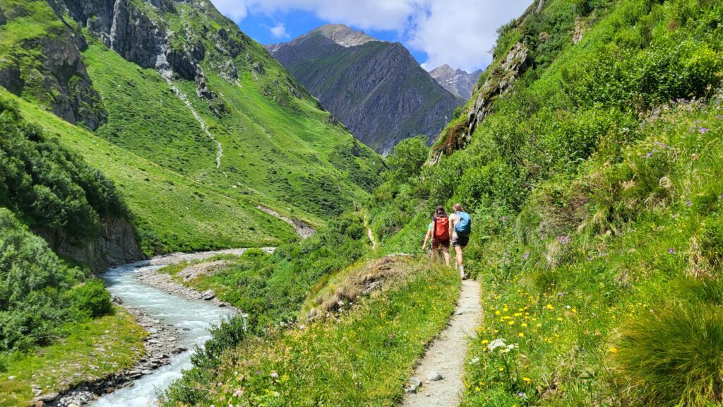Bild zeigt Menschen einen Fluss in den Bergen und Menschen, die wandern
